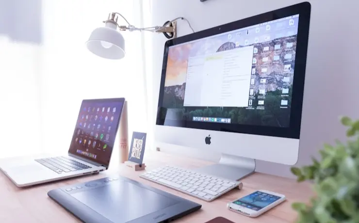 Modern desk setup with an iMac, MacBook, graphics tablet, keyboard and smartphone in a bright workspace