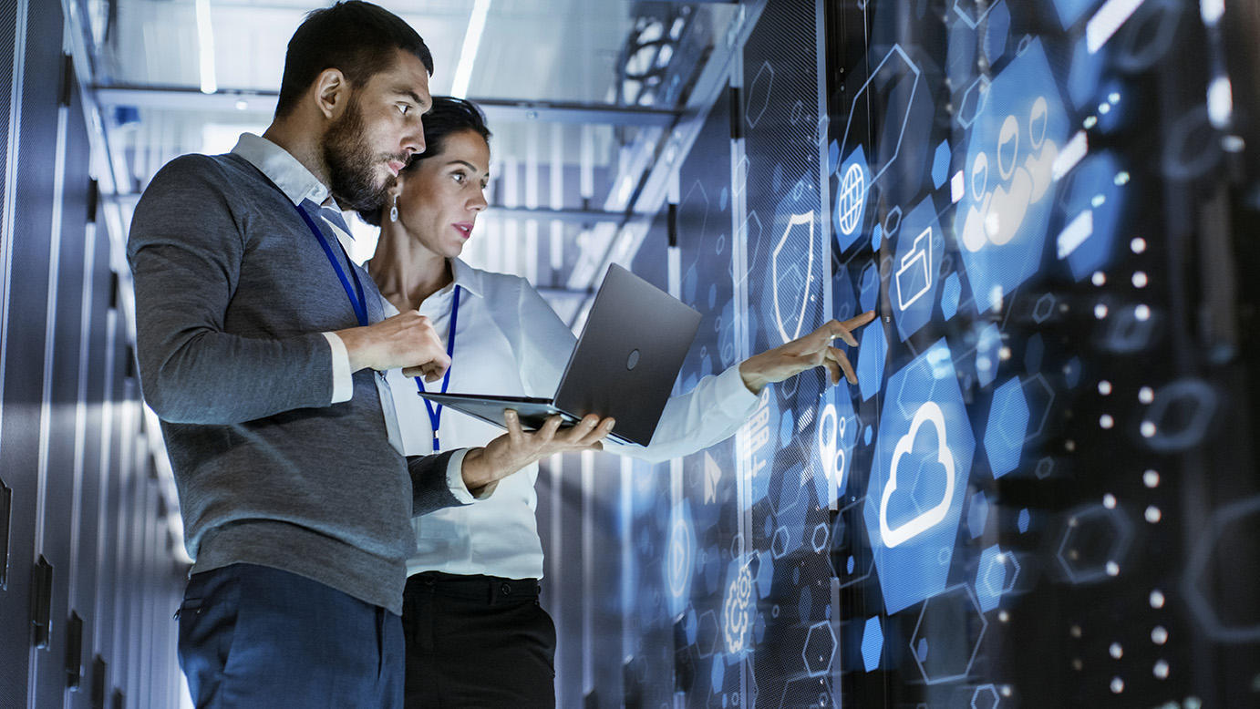 IT professional examining server infrastructure in a dimly lit data center with blue lighting