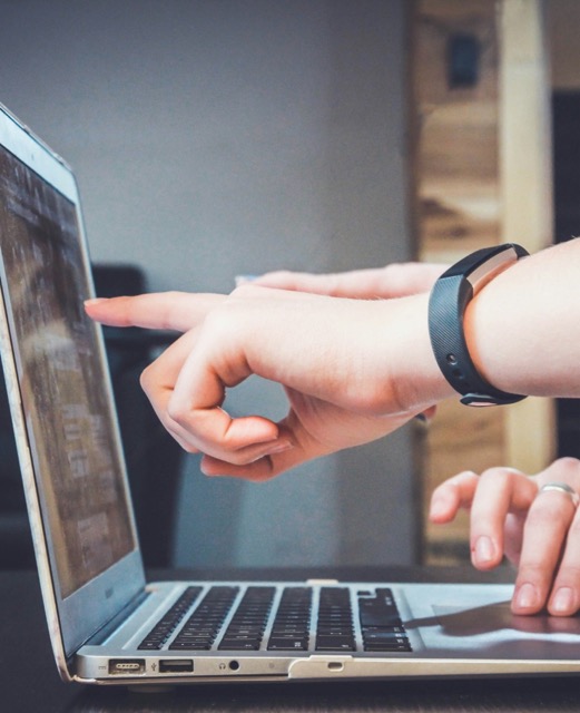 Person pointing at a laptop screen during a business meeting or presentation