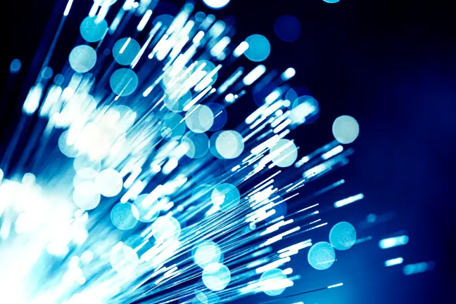 Closeup of illuminated fiber optic cables with blue light and bokeh effects against a dark background