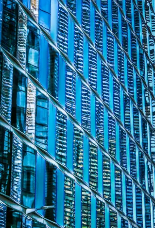 Abstract architectural detail of a modern glass building facade with geometric blue reflective patterns